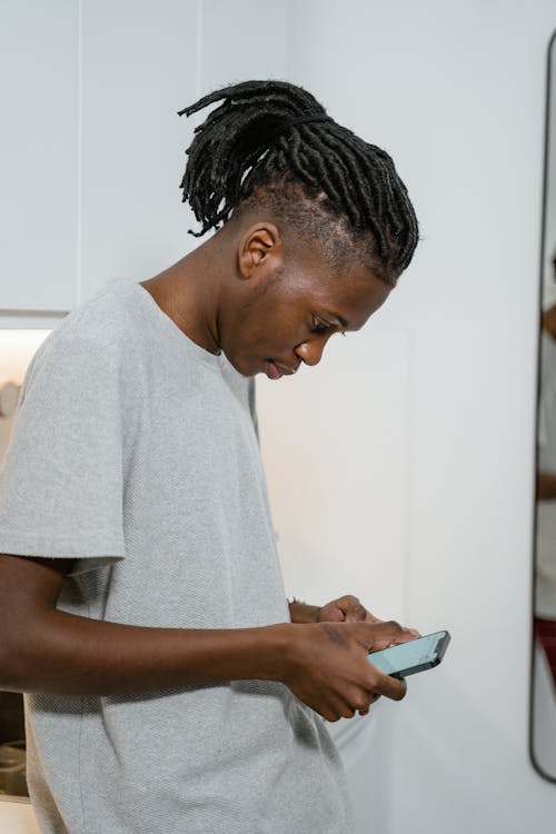 Man in Gray Crew Neck T-shirt Using a Smartphone