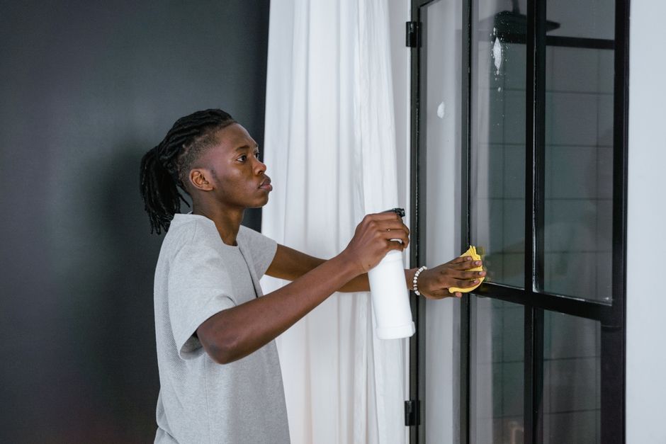 Person cleaning a glass door with a dog sitting nearby, showing safety for pets - non toxic glass cleaner Person cleaning a glass door with a dog sitting nearby, showing safety for pets - non toxic glass cleaner