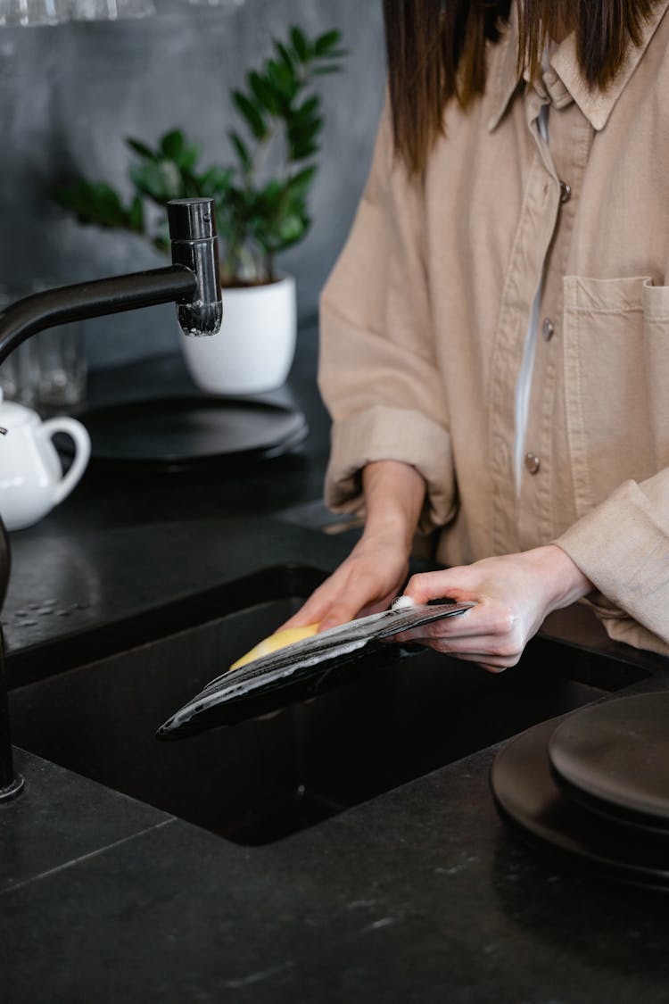 A Person Washing The Dishes