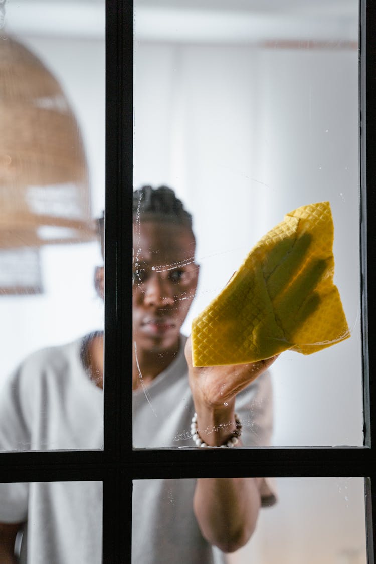 A Man Wiping A Window With A Cleaning Cloth