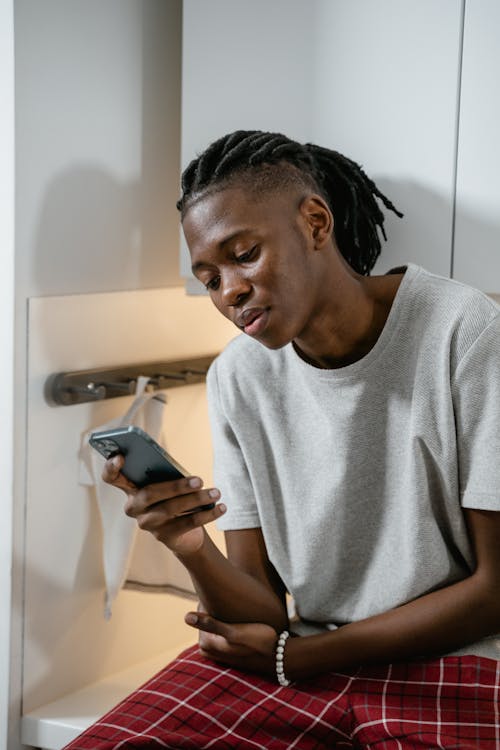 Free A Man in Gray Shirt Using a Smartphone Stock Photo