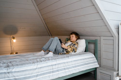 Free Boy in Yellow and Black Plaid Shirt Lying on Bed Stock Photo