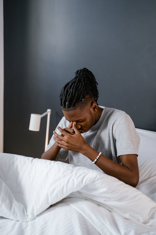 Man in Gray Shirt Sitting on the Bed