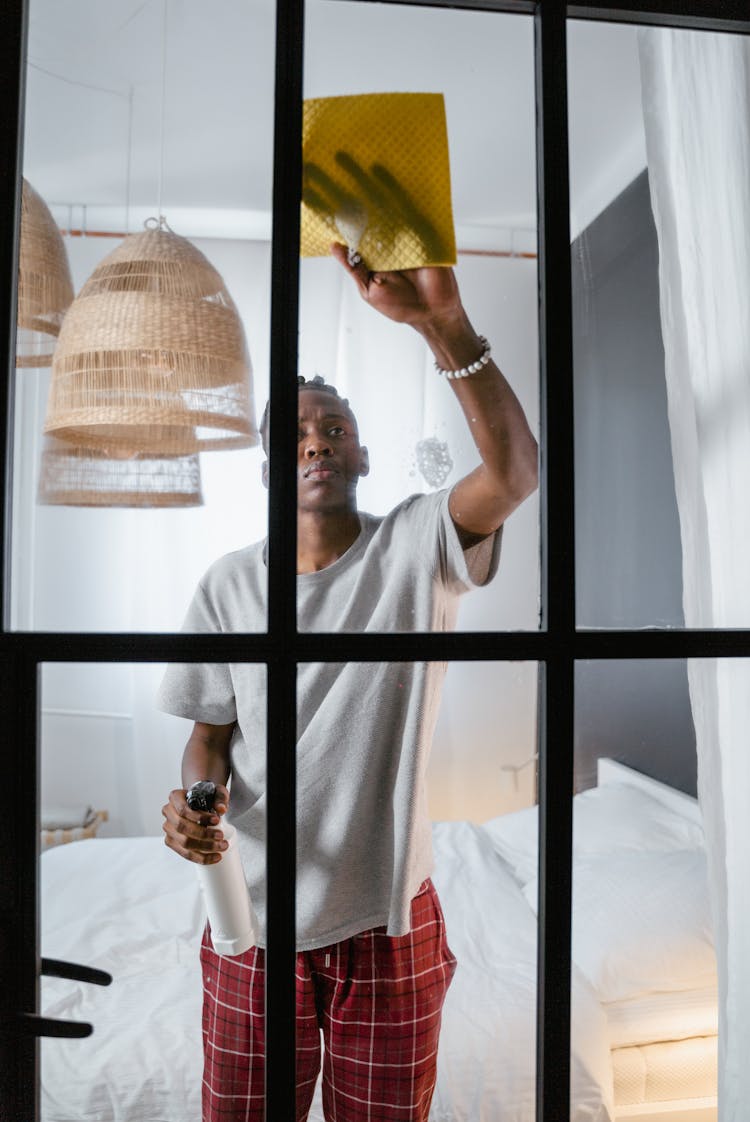 A Man In Gray Shirt Cleaning The Window