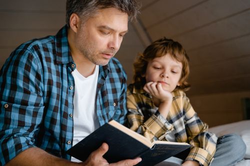 Free A father and son sharing a tender moment reading a bedtime story together. Stock Photo