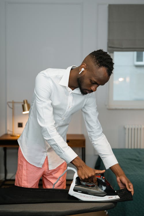 Free A Man in the Bedroom Ironing Clothes Stock Photo