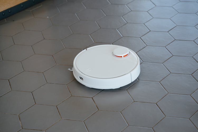 White Round Robot Vacuum On Gray Tiled Floor