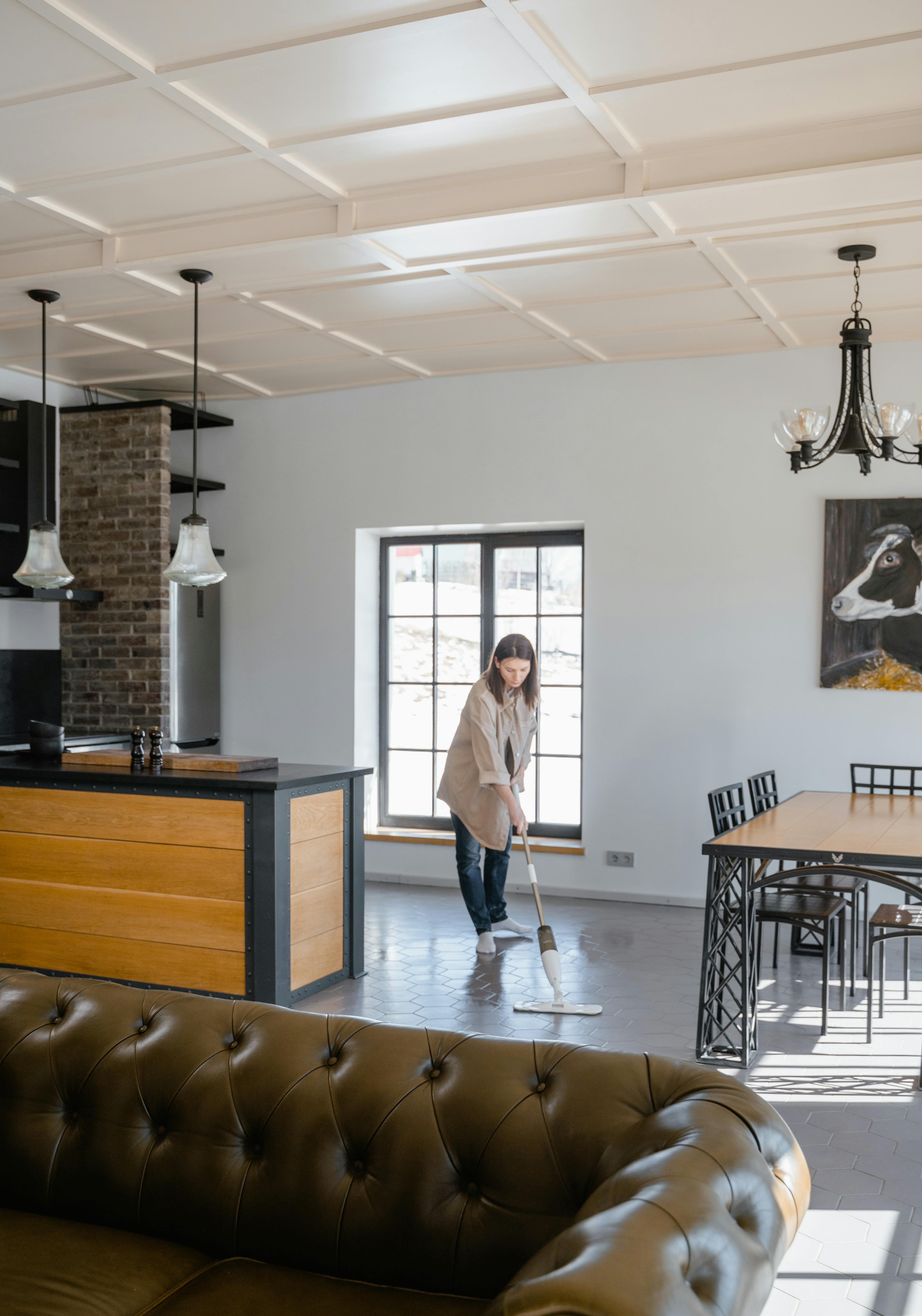 Woman mopping hardwood floor in modern living room