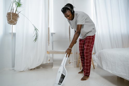 Free Man using Vacuum Cleaner to sweep the Floor Stock Photo