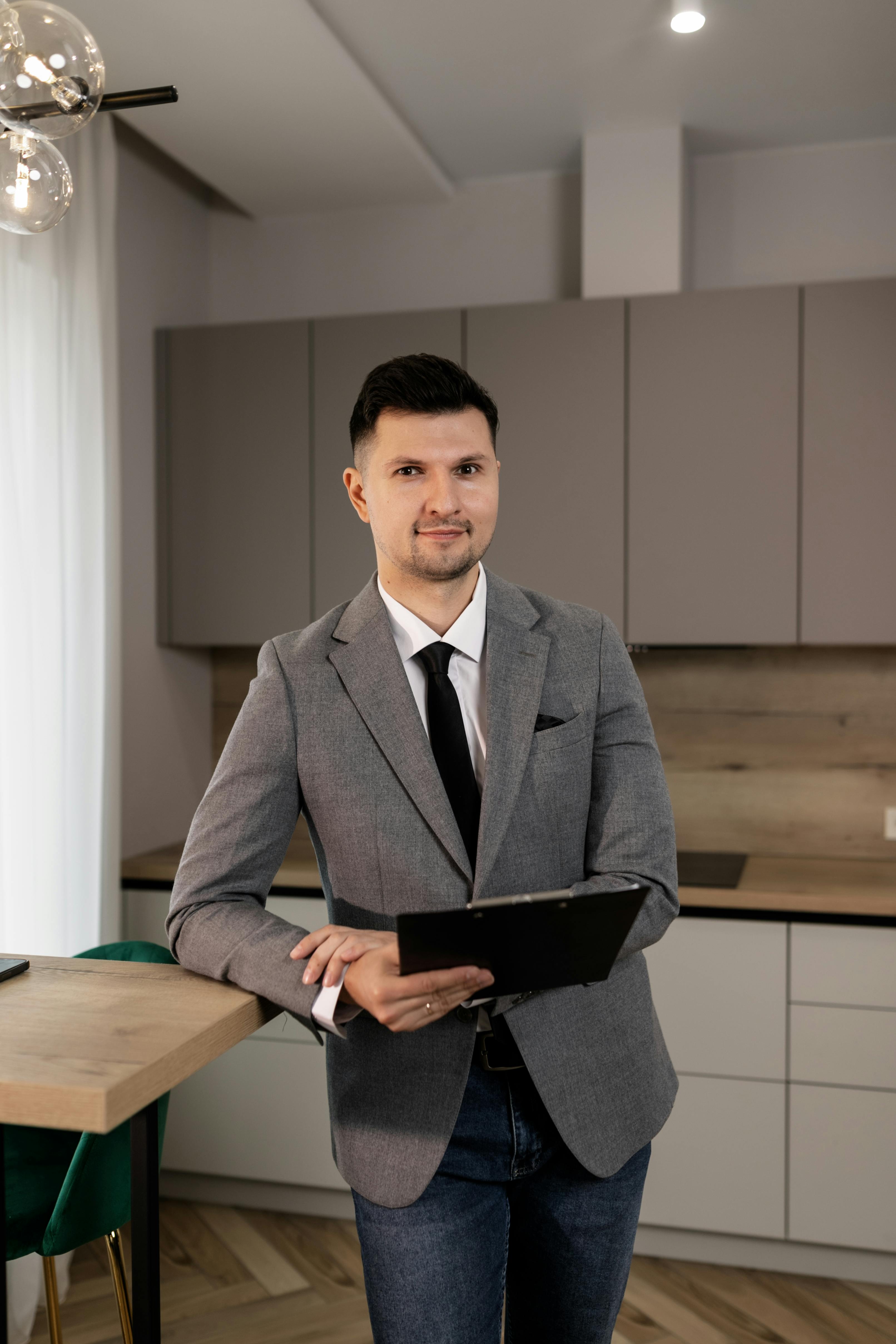 man in gray suit jacket holding black folder