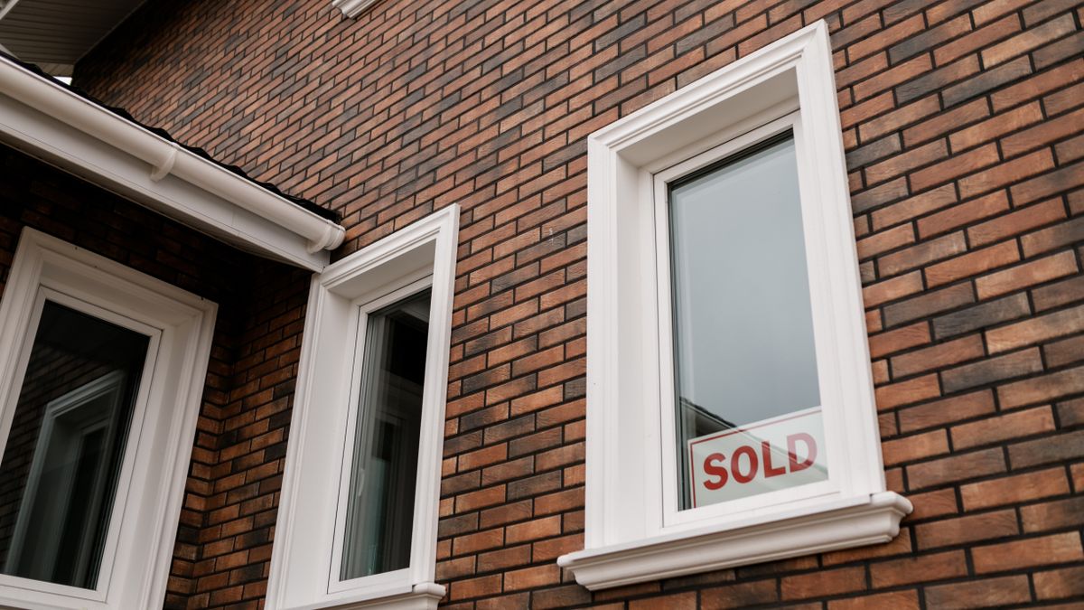 Panneau SOLD devant une maison en brique