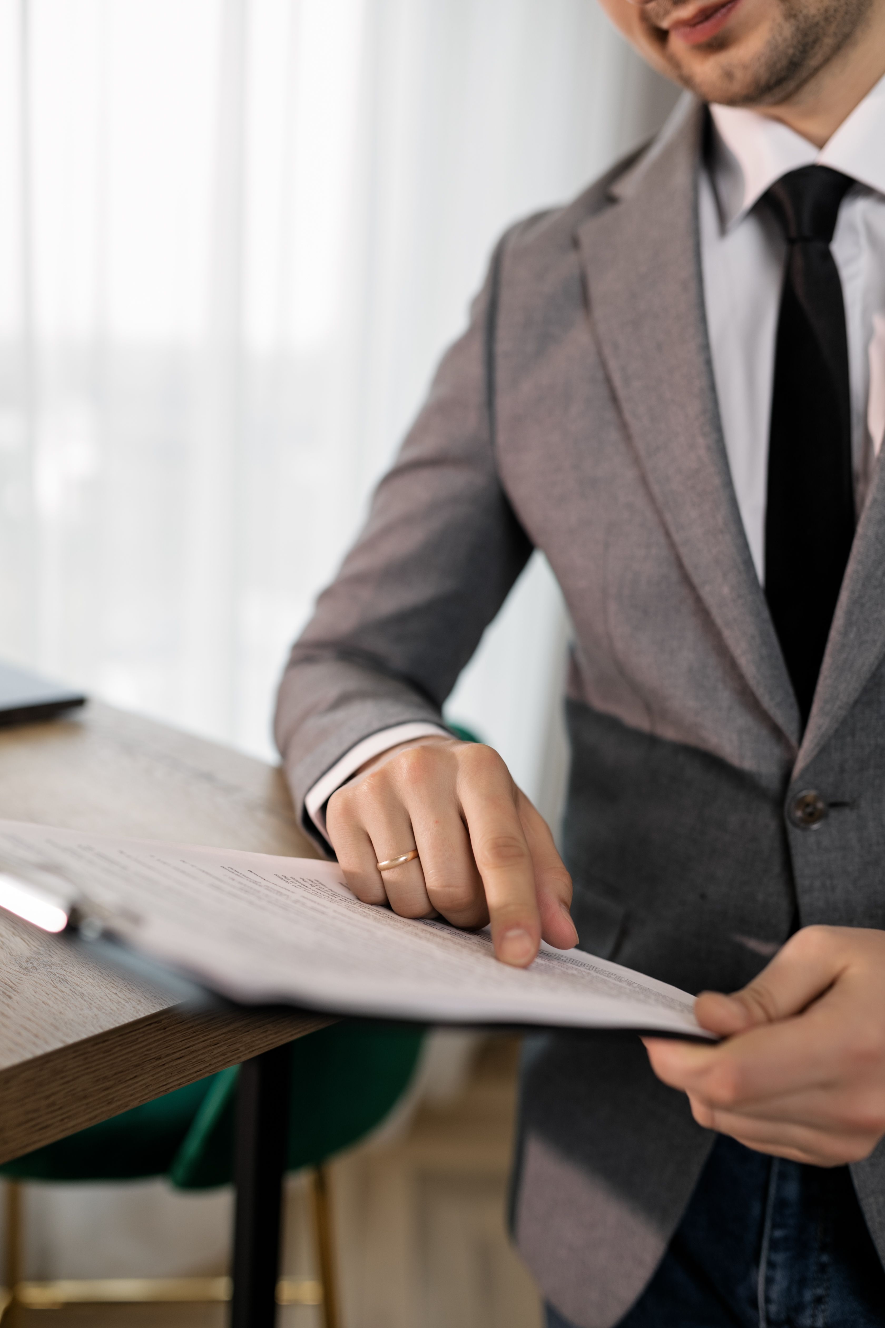 A man in a grey suit jacket pointing at text on papers