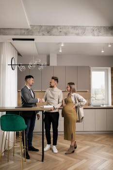 A young couple meets a realtor in a stylish kitchen to discuss buying a new home.