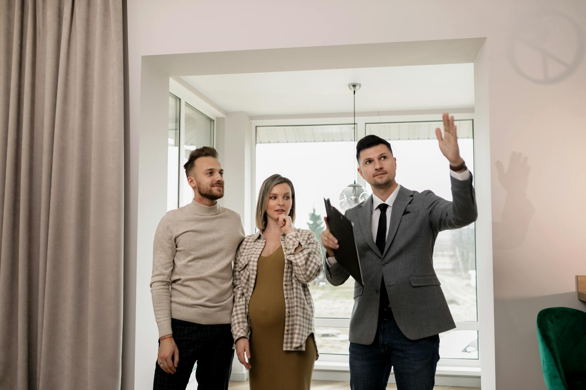 A pregnant woman and her partner explore a new house with a real estate agent.