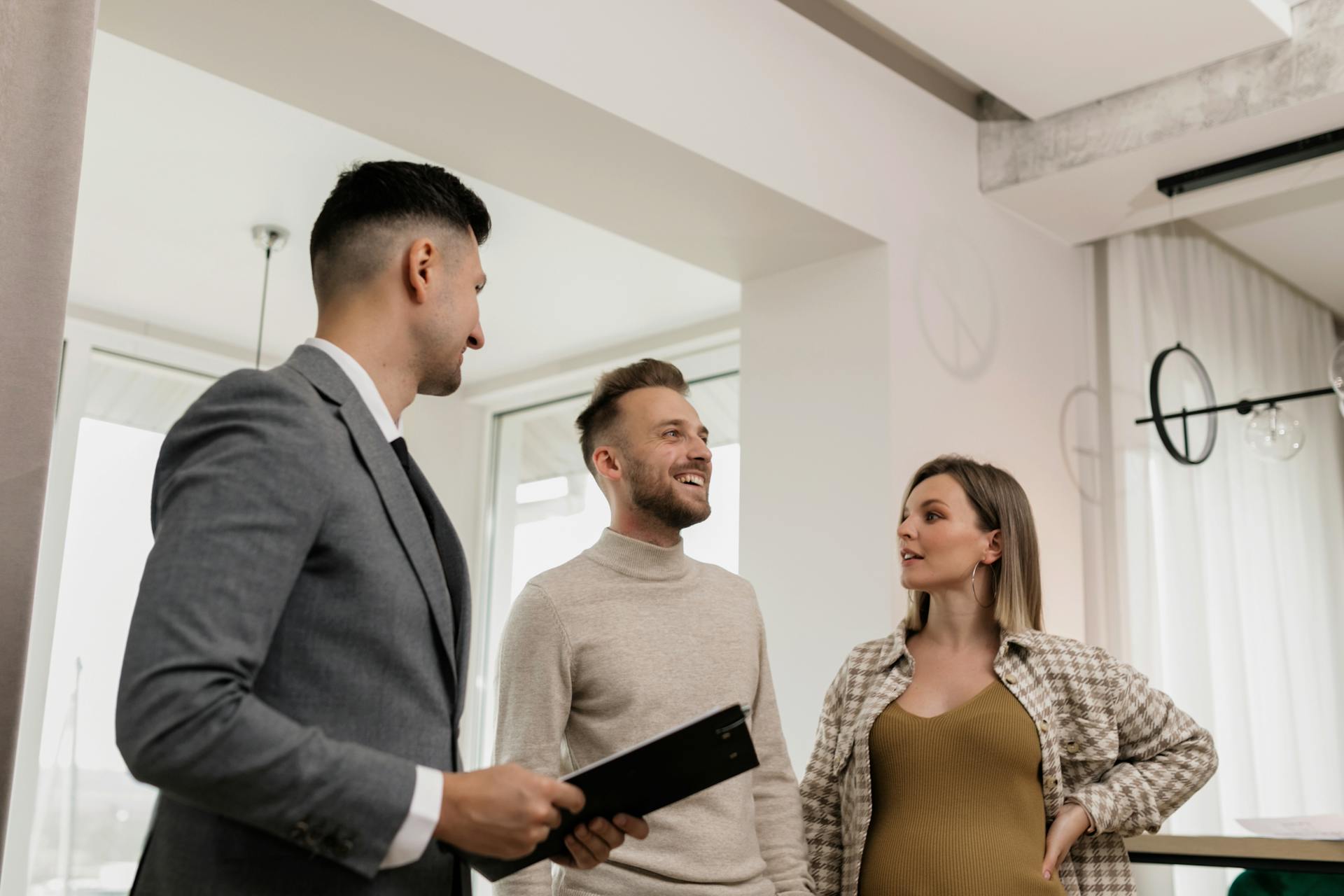 A couple consults with a real estate agent indoors, showcasing an exemplary customer service moment.