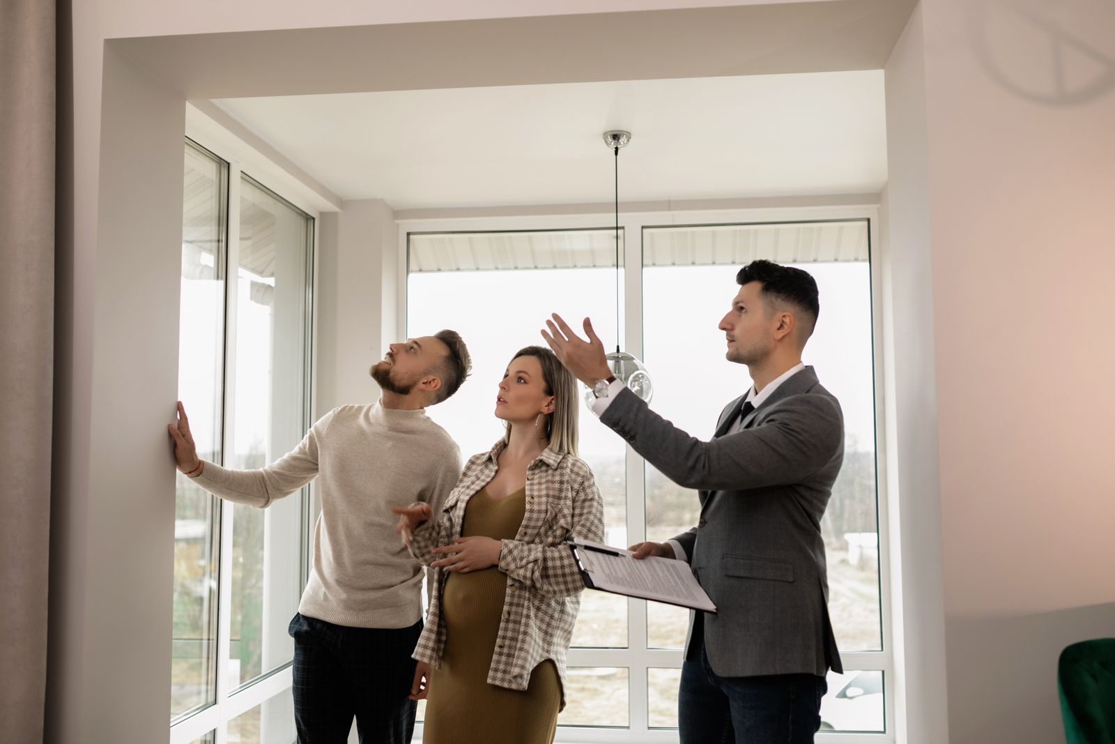 Free A young couple inspects a modern apartment with a real estate agent during a daytime viewing. Stock Photo