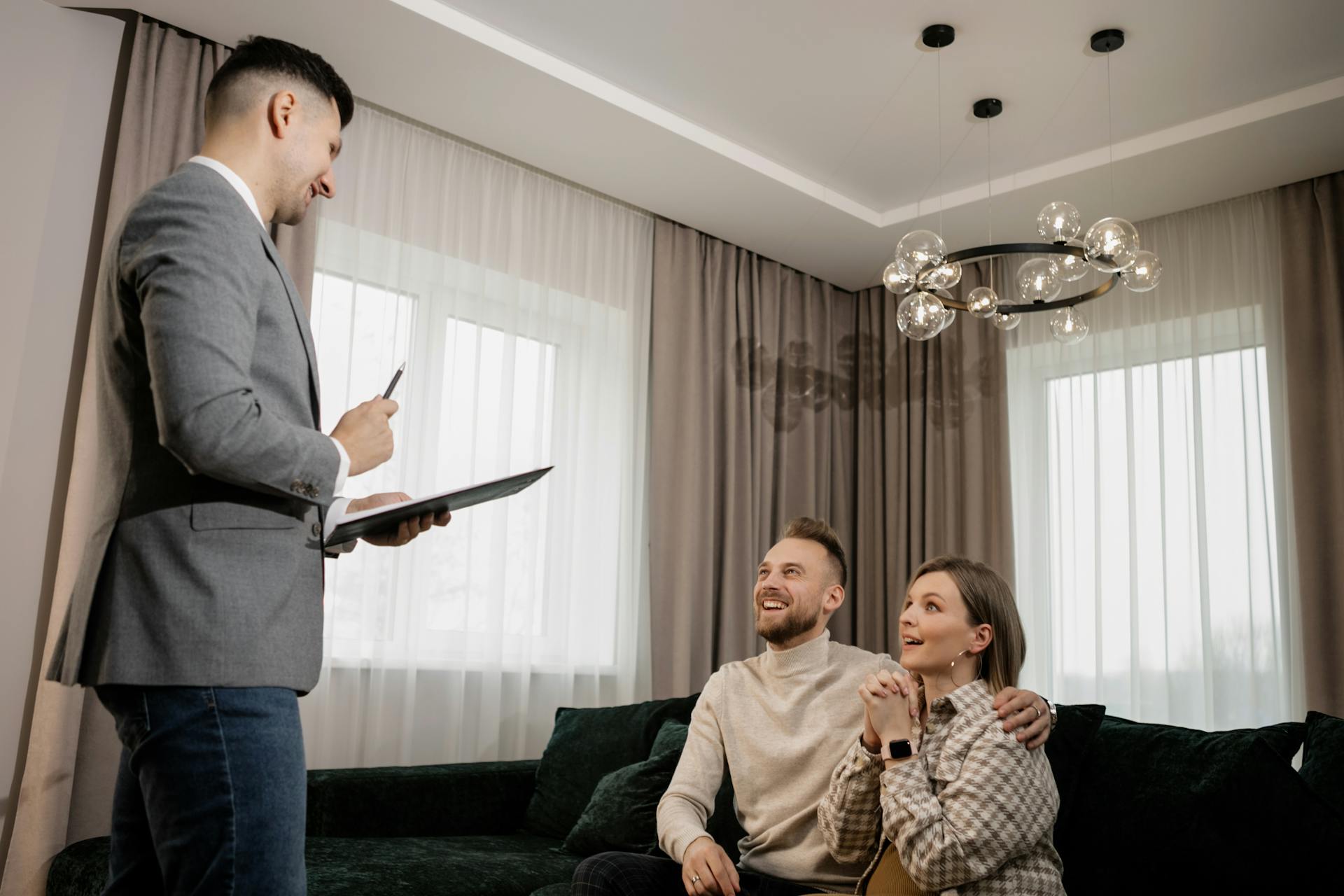 A couple meeting with a real estate agent discussing property in a modern living room.