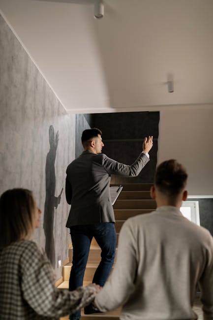 A real estate agent leads a couple on a house tour, highlighting interior features in a modern home.