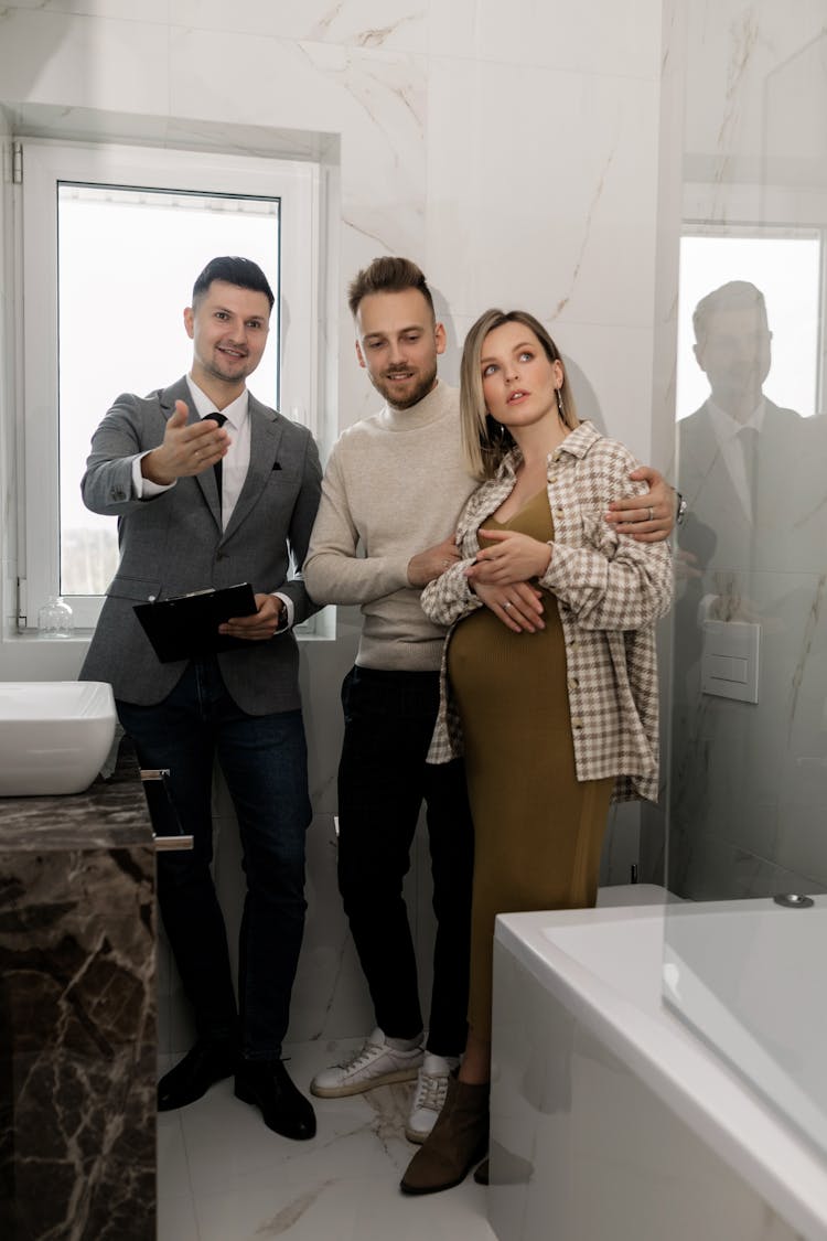 A Couple With A Realtor Looking At A Bathroom Inside A House