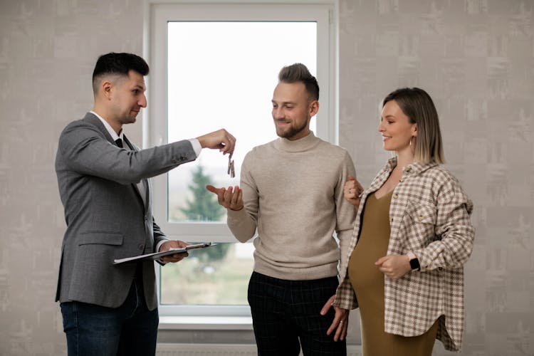 A Real Estate Agent Handing The Key To The New Homeowners