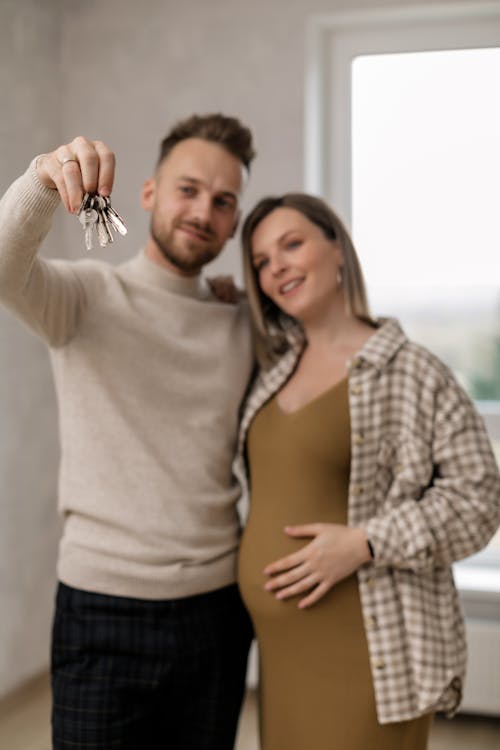 Free Man Holding Keys Beside a Pregnant Woman Stock Photo
