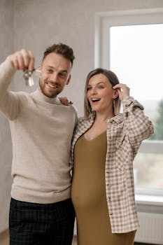 Excited couple holding keys to their new home, celebrating together indoors.