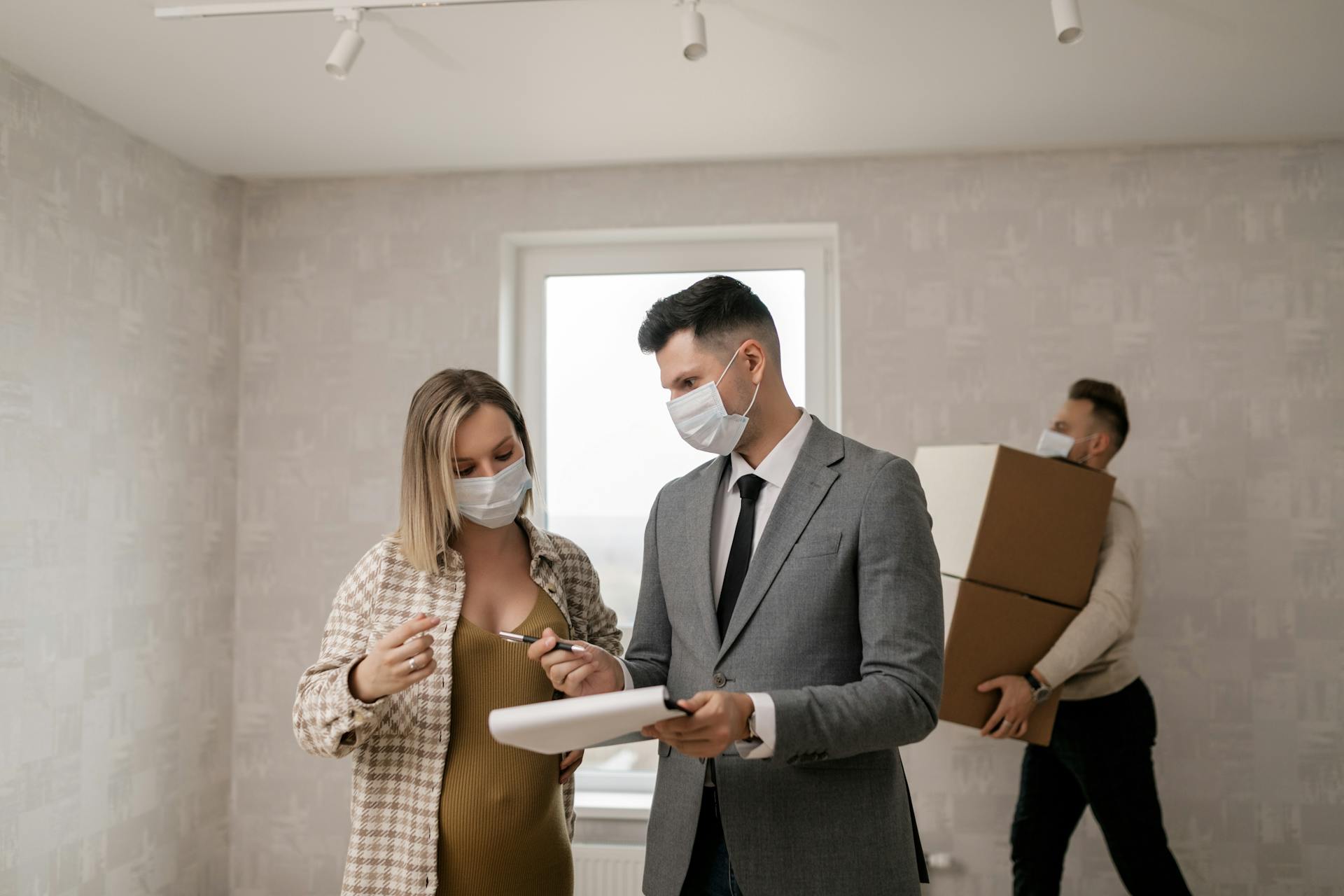 A real estate agent consulting with clients in a new home during a pandemic.