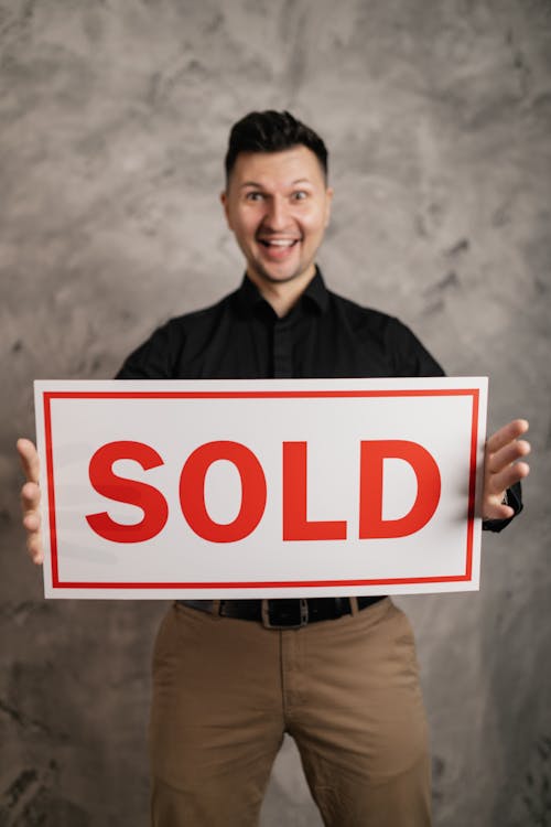 Man in Black Long Sleeve Shirt Holding a Signboard