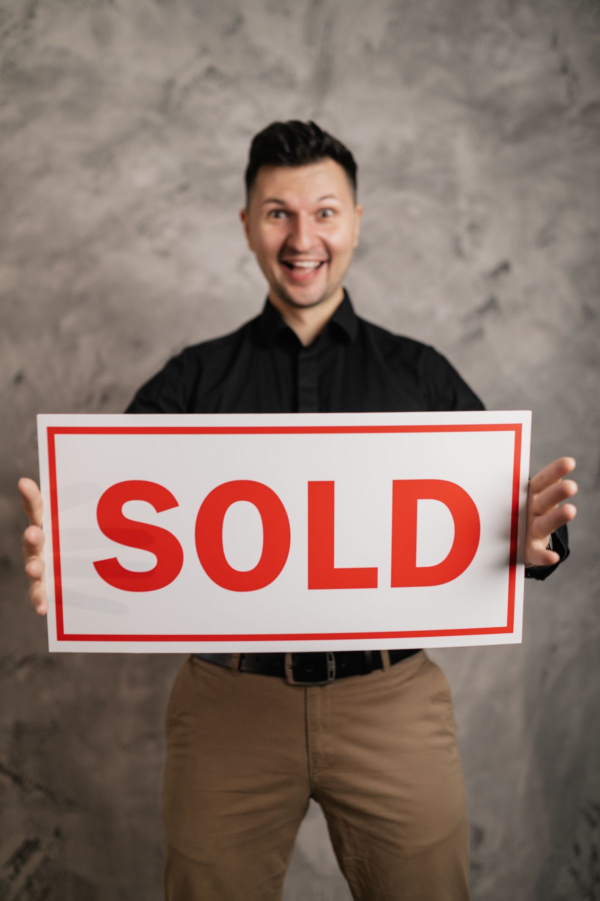 Man holding 'sold' signboard