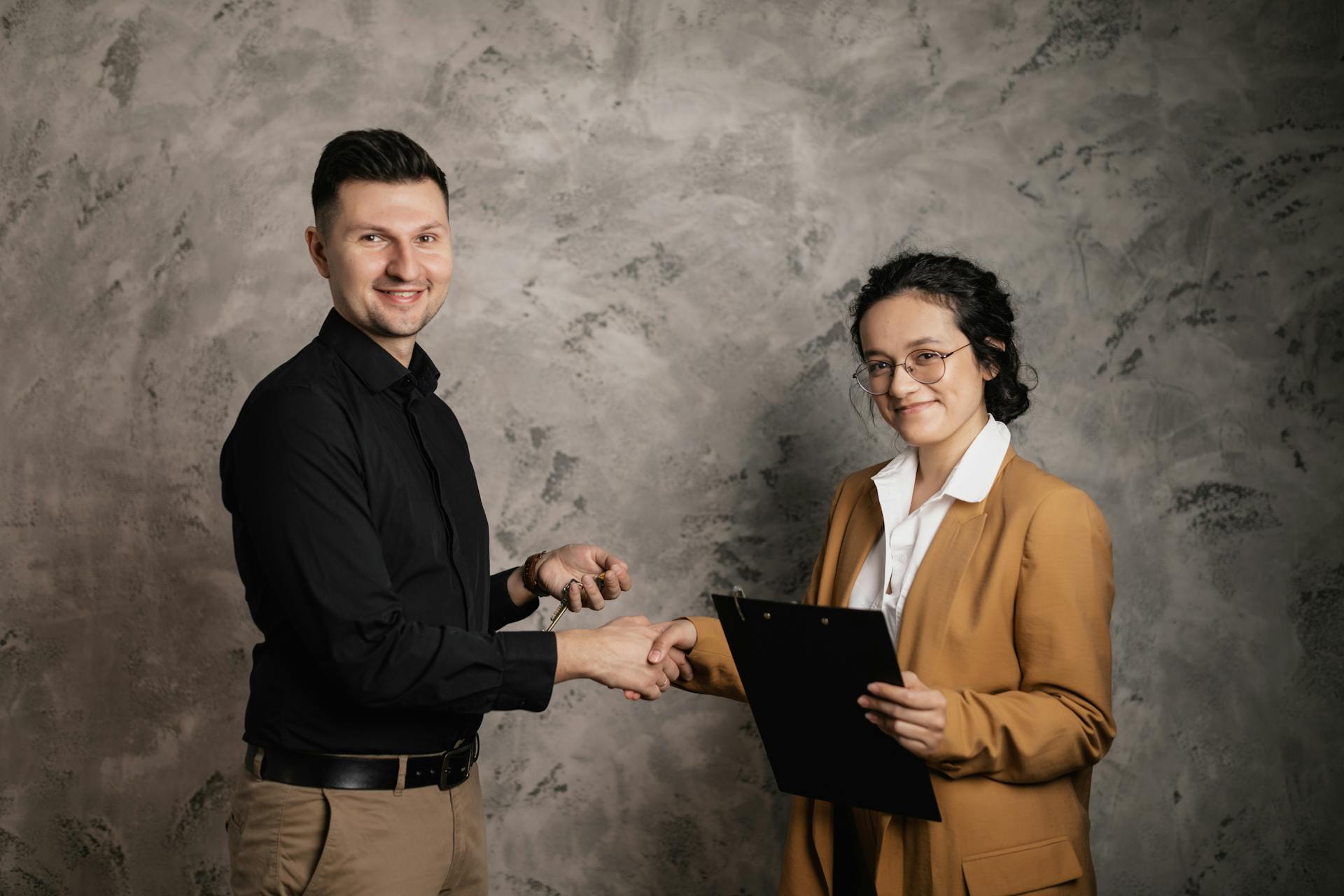 Man and woman shaking hands in a business agreement indoors, smiling confidently.