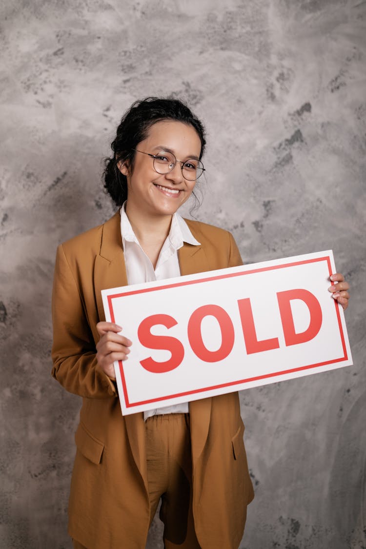 Smiling Woman Holding A Sold Sign