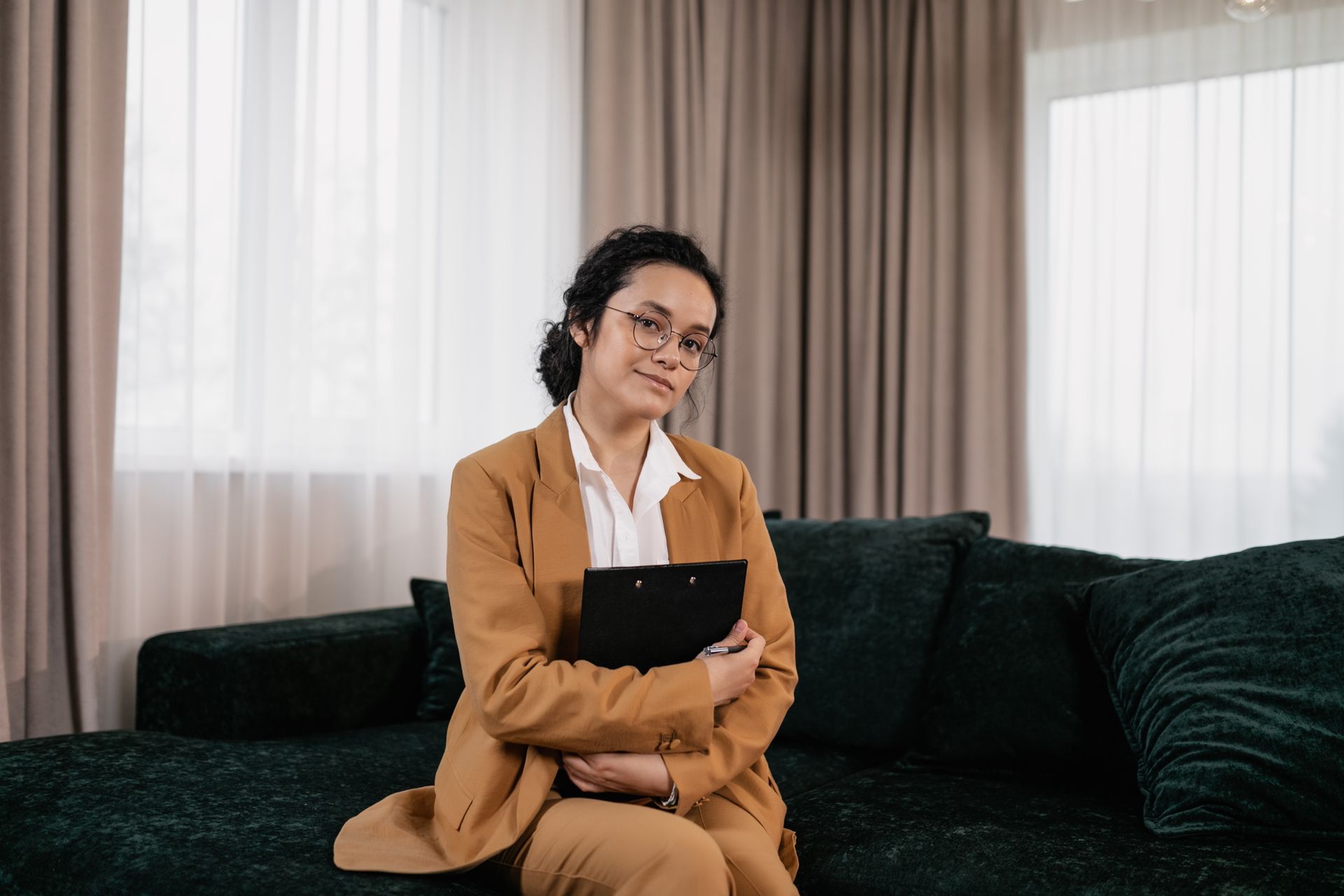 Confident woman in business attire sits on a sofa, exuding professionalism.