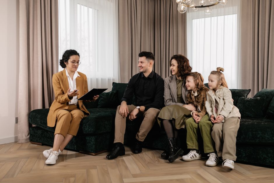 Family discussing home purchase options with real estate agent indoors.