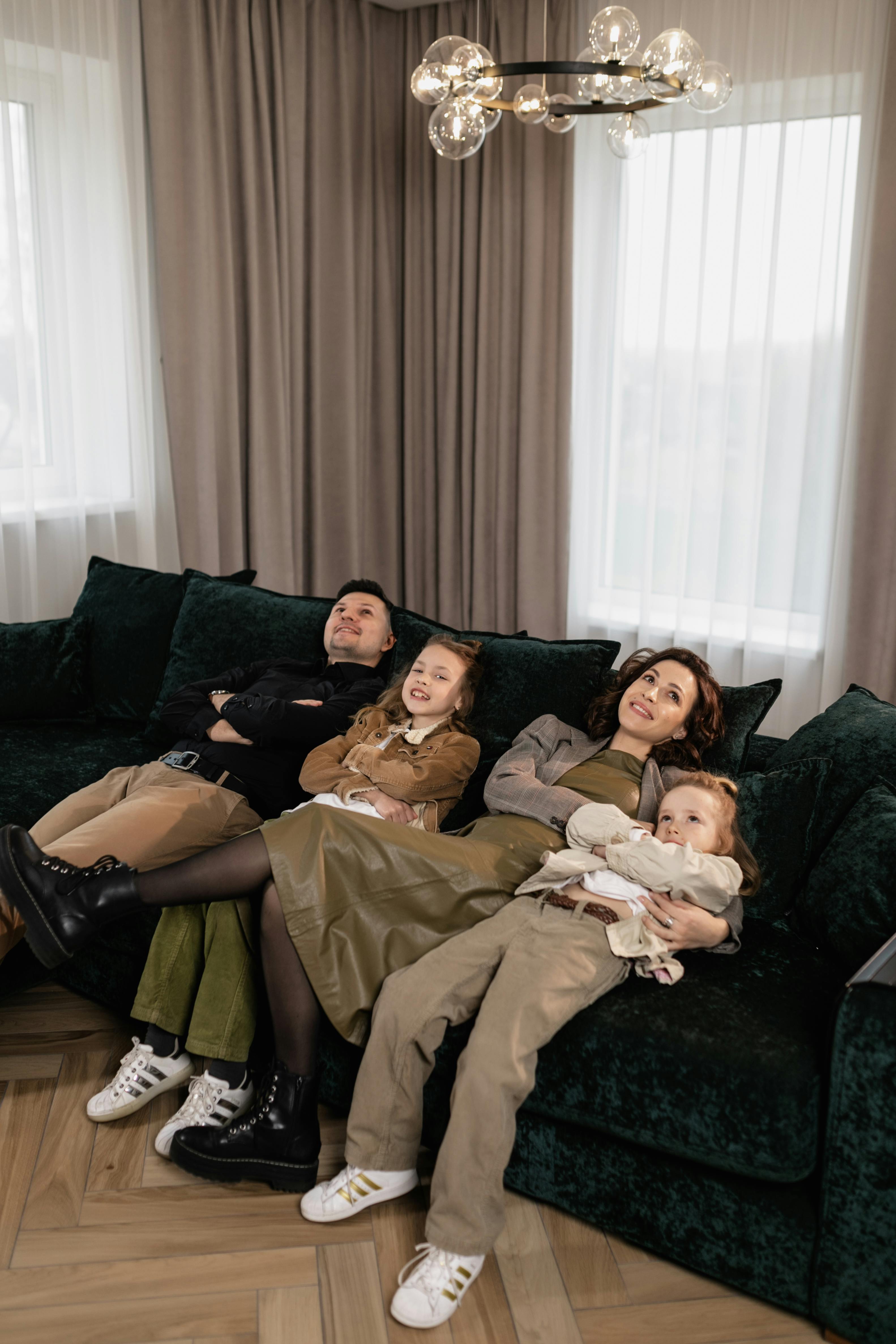 happy family sitting on dark green sofa
