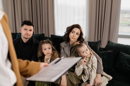 Free A family attentively listens during a consultation in a cozy living room setting. Stock Photo