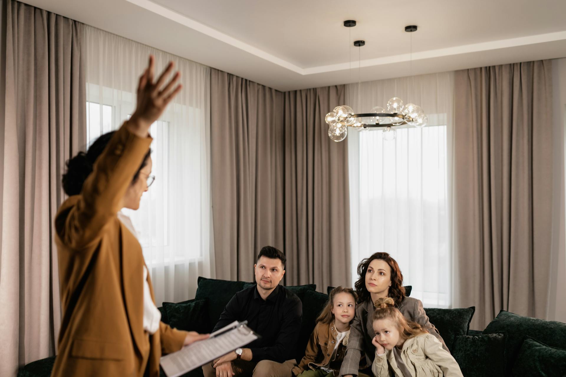 A family in a living room listens to a real estate agent discussing a new home purchase.