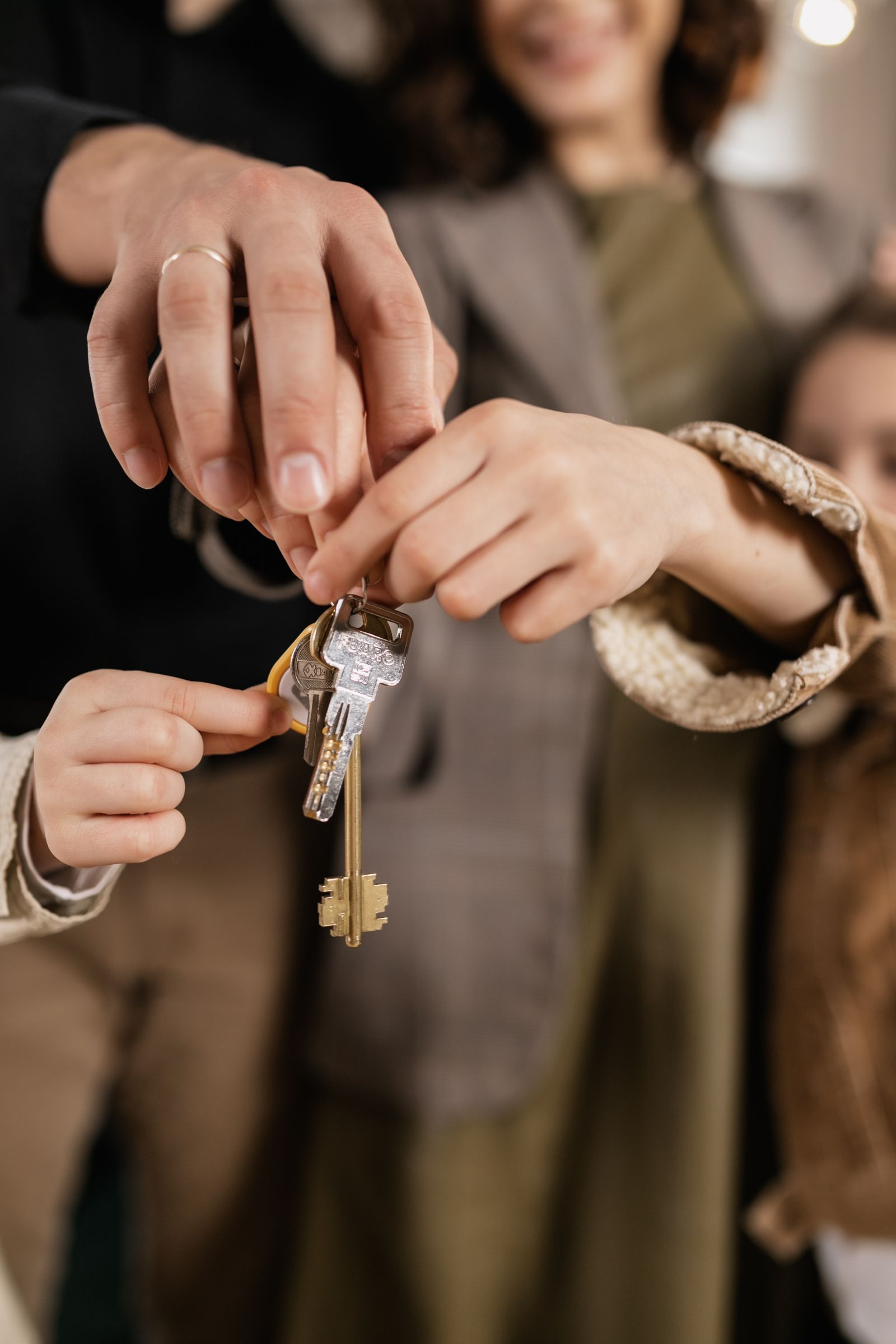 Free Close-up of a family holding house keys, symbolizing home ownership. Stock Photo