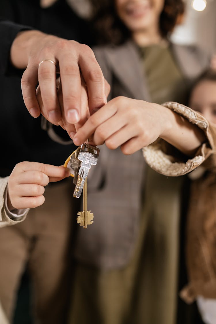 People Holding A Set Of Keys Together