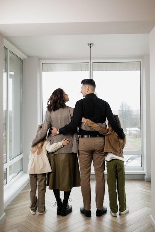 Free A Family Standing Near the Glass Windows of the House Stock Photo