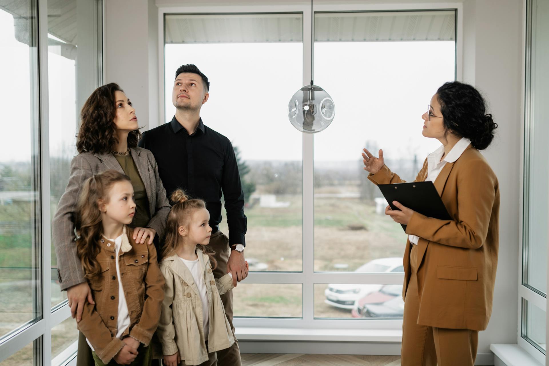 Family with children visits potential new home with a realtor inside modern house.