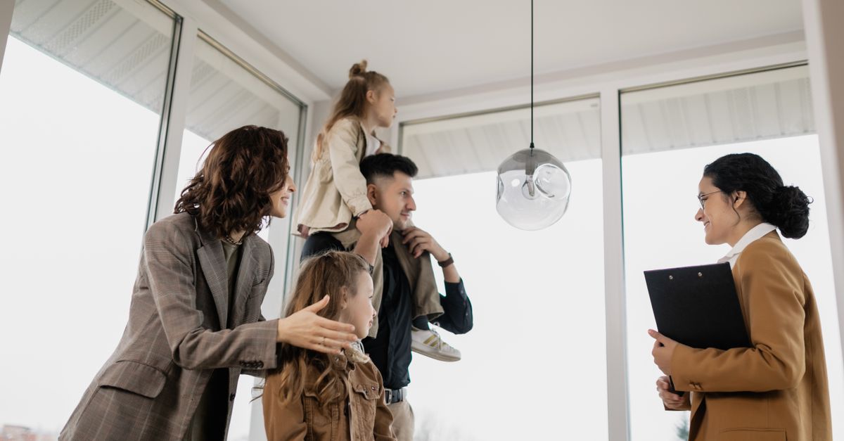 A family with children excitedly tours a modern home guided by a real estate agent.
