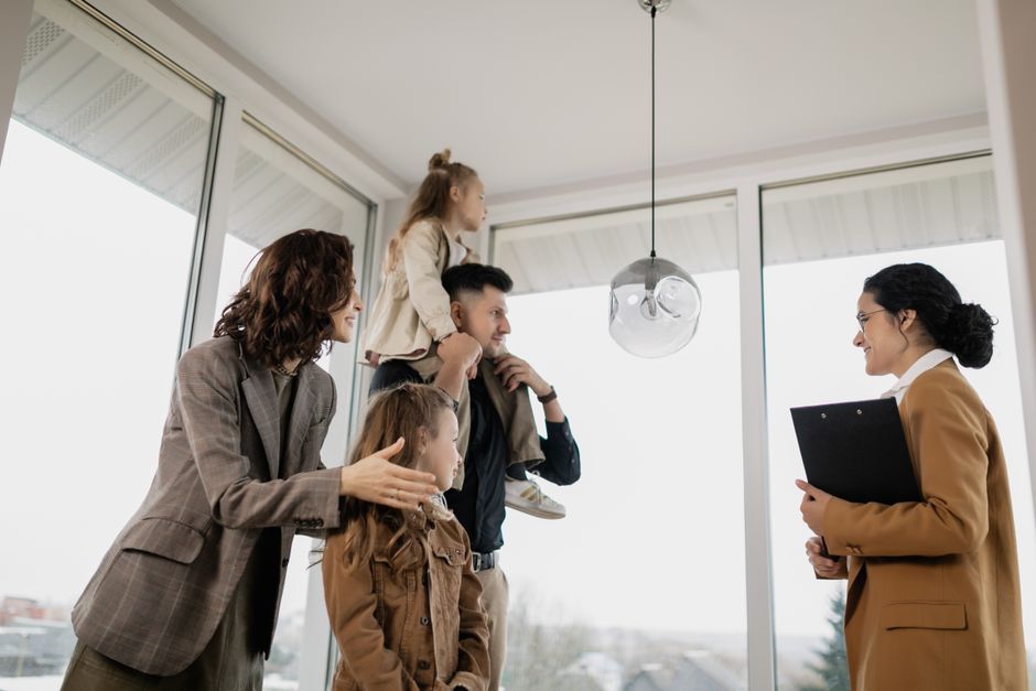 Una familia con niños visita emocionada una casa moderna guiada por un agente inmobiliario.