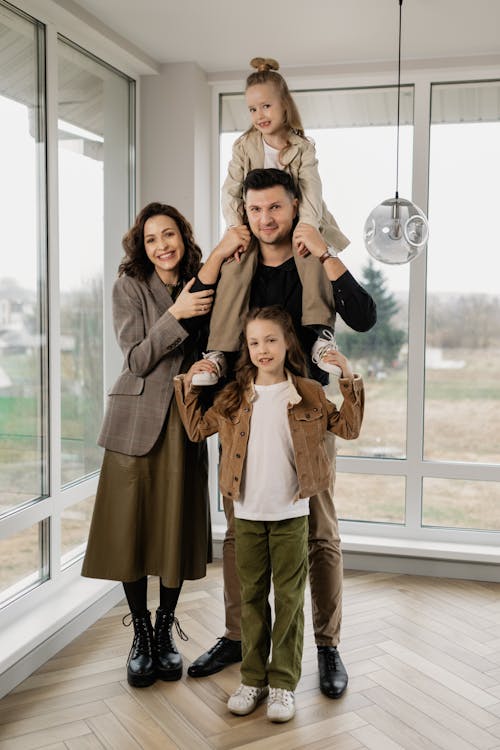 Free A Man Carrying a Kid on to His Shoulder While Standing Beside a Girl and a Woman Stock Photo
