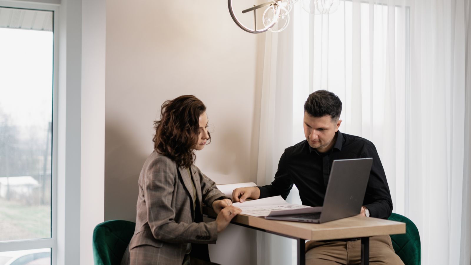 Two people reviewing papers beside a laptop at a table
