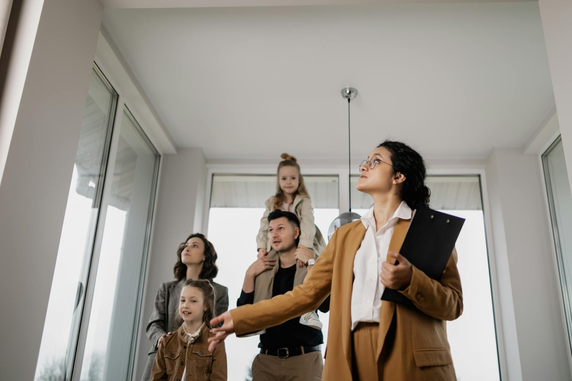 A family with children tours a modern home guided by a real estate agent.