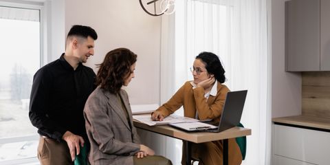 A couple consults a real estate agent in a modern office setting.