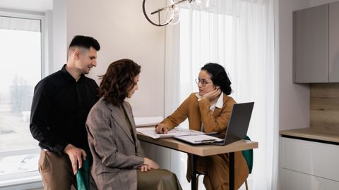 A couple consults a real estate agent in a modern office setting.