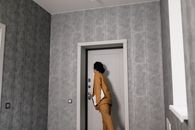 Woman in Brown Coat and Brown Pants Standing in Front of Door