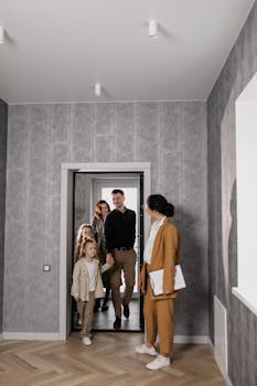 A family enters a new home with a real estate agent welcoming them inside.