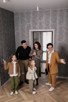 A family of four joyfully exploring their new home with a real estate agent.